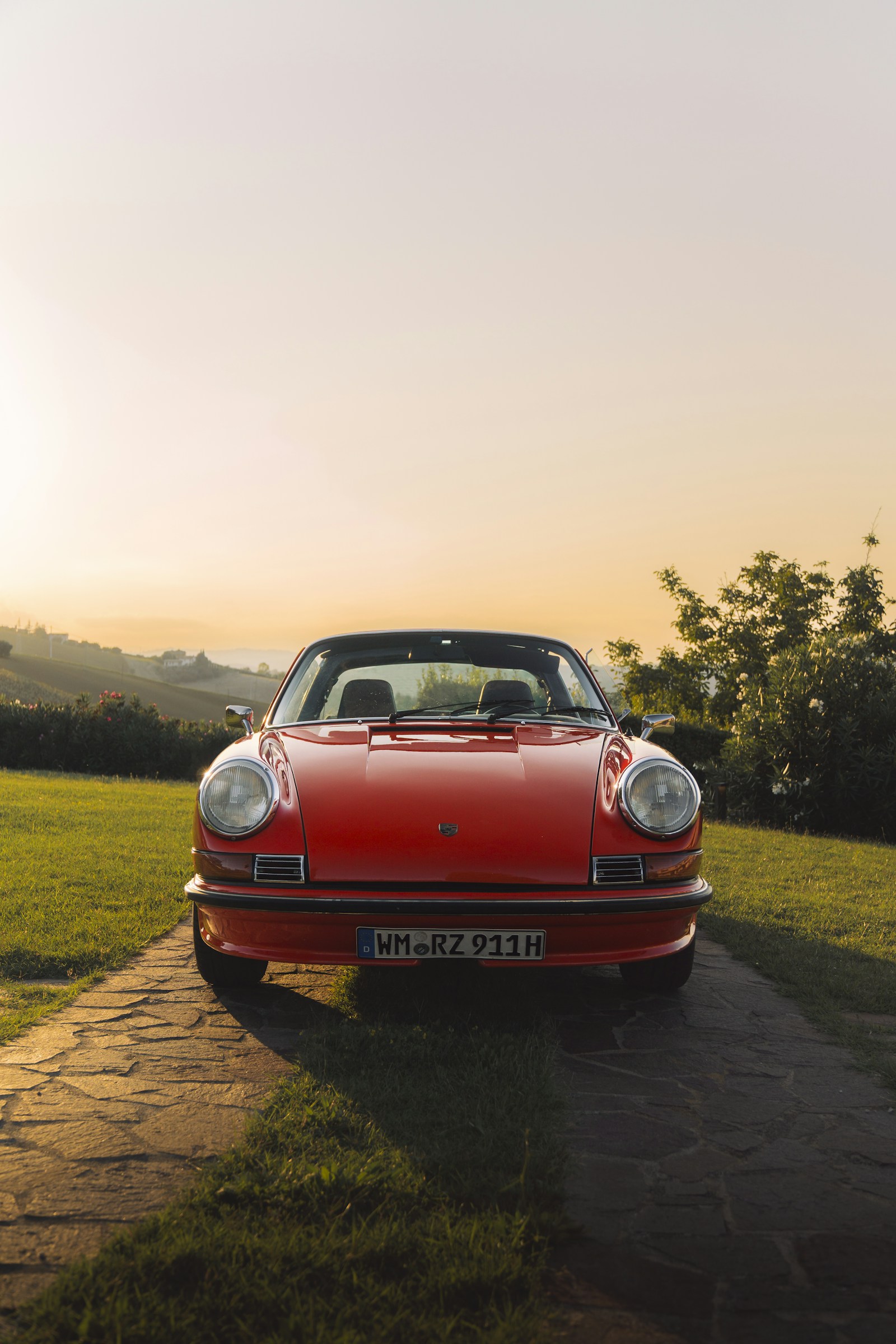 Red classic Porsche 911 parked on a stone driveway